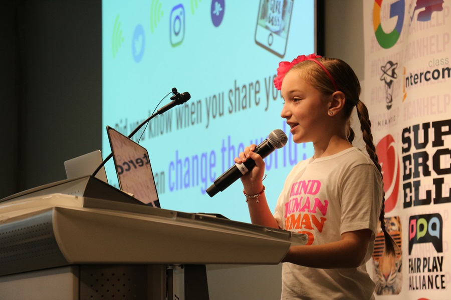 young smiling blond girl speaks into mic