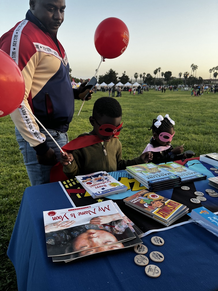 Father helps children choose books at United Through Reading event