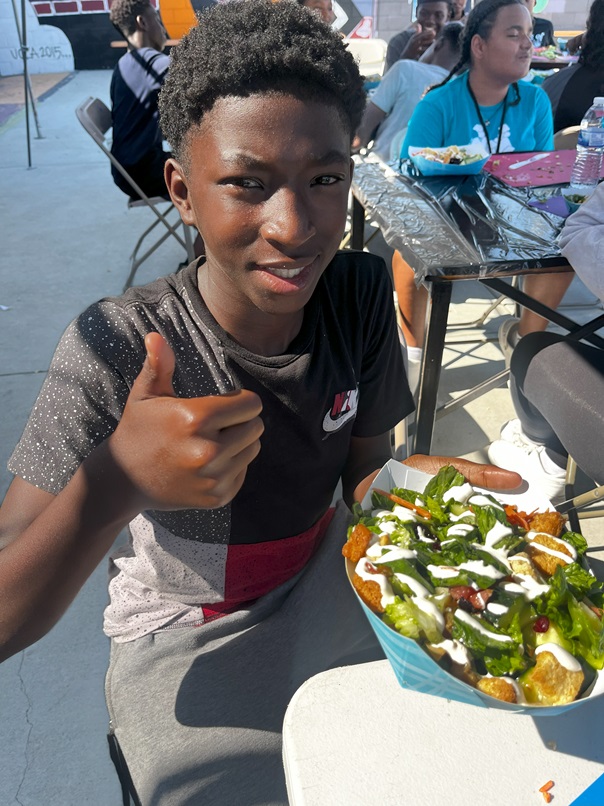 smiling boy thumbs of plate of healthy food at Al wooten Jr. youth center