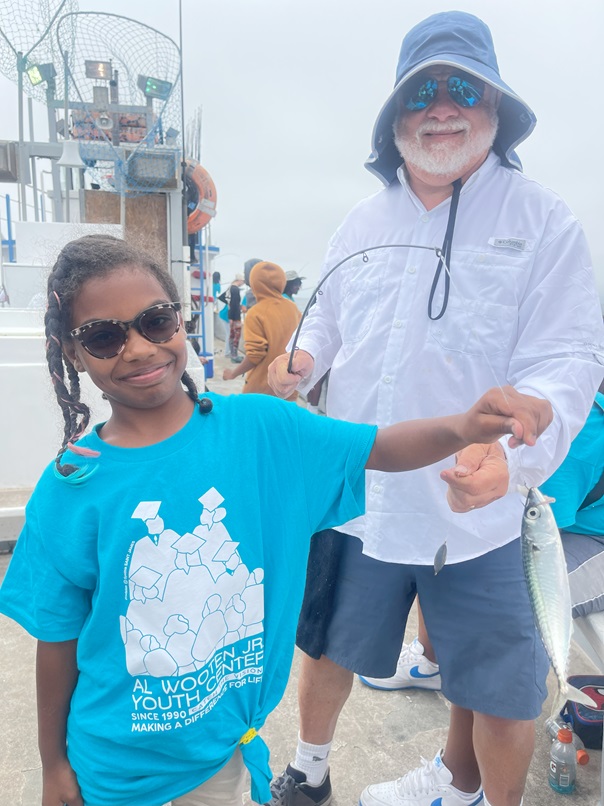 Smiling girl shows off the fish she caught at the Wooten Center summer camp