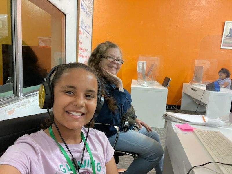 smiling girl does homework at the Al Wooten Jr. Youth Center while wearing earphones