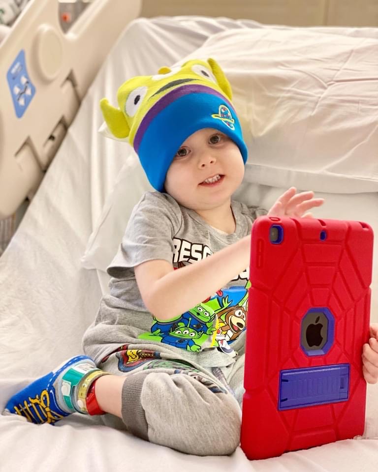 pediatric cancer patient plays with apple computer game in hospital bed