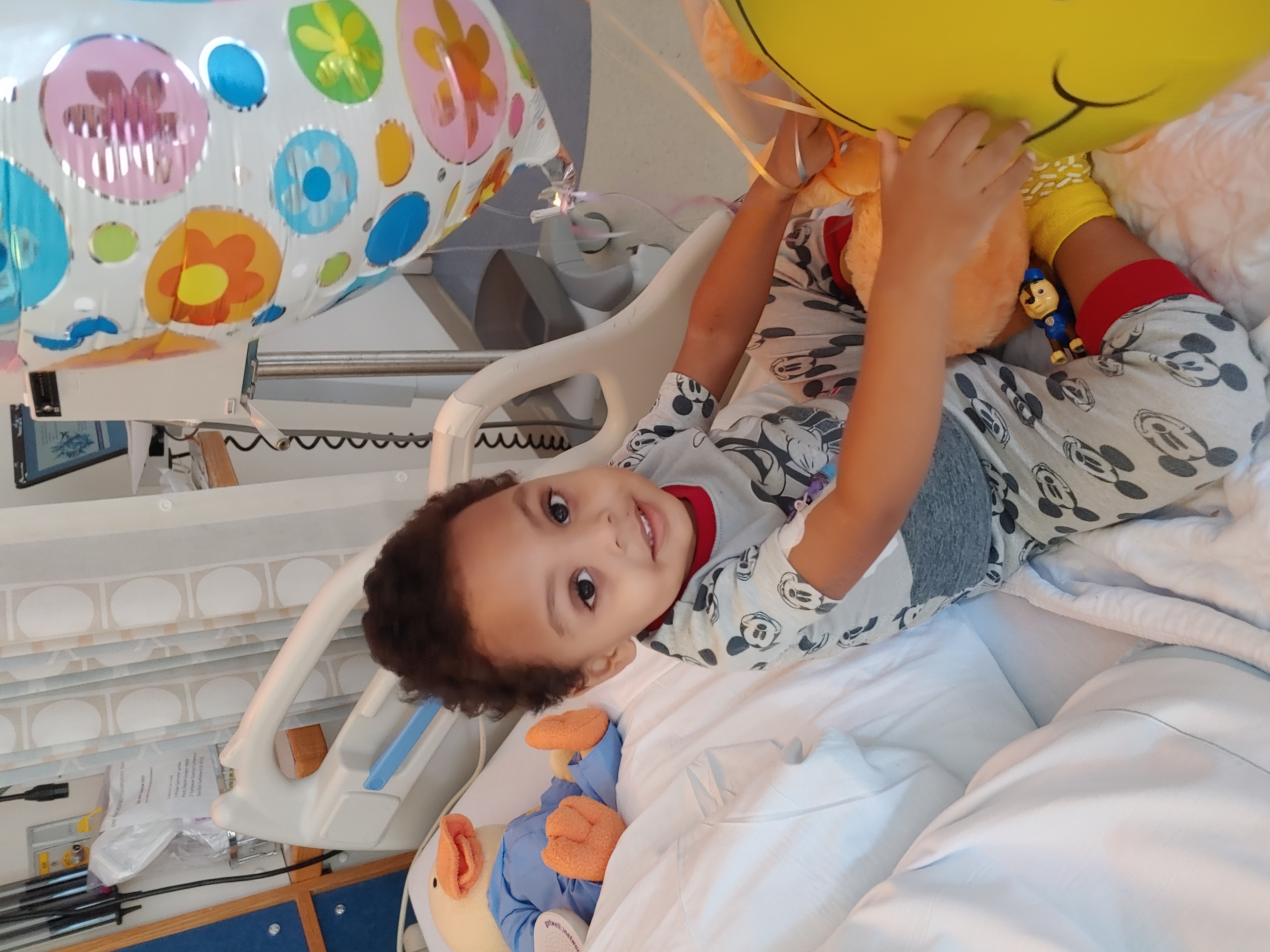 pediatric cancer patient plays with toy in hospital bed. The National Children's Cancer Society