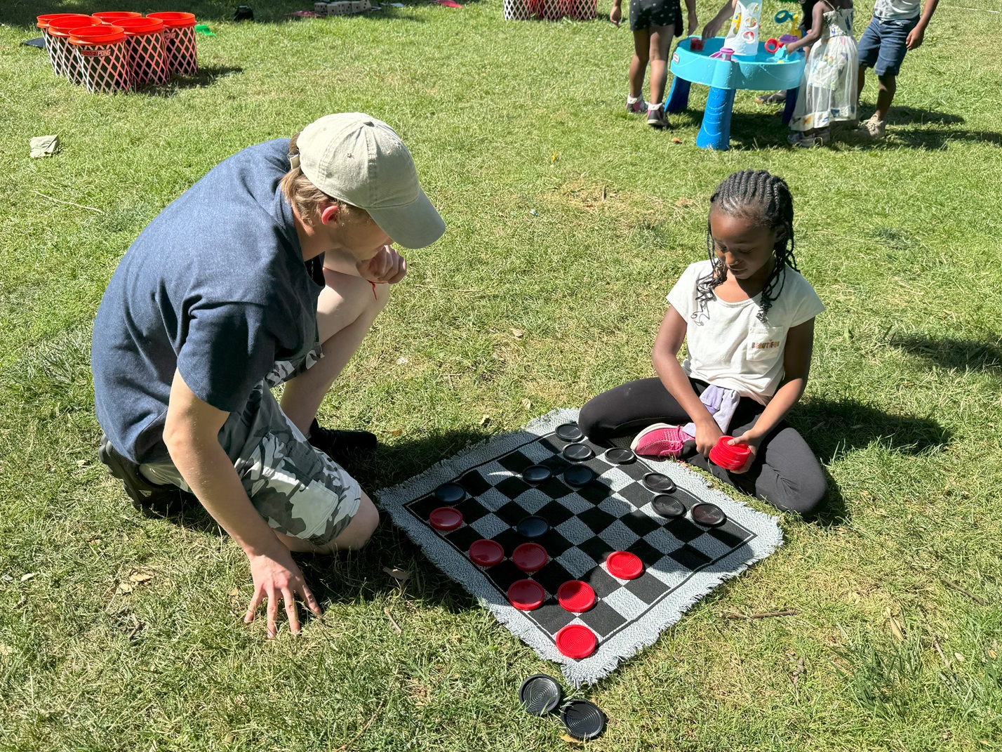 Girl plays checkers in park with mentor. Folsom Cordova Community Partnership