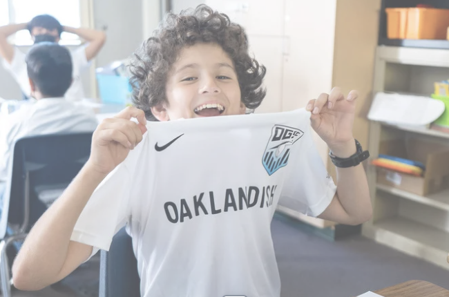 Boy holds oakland genesis t-shirt