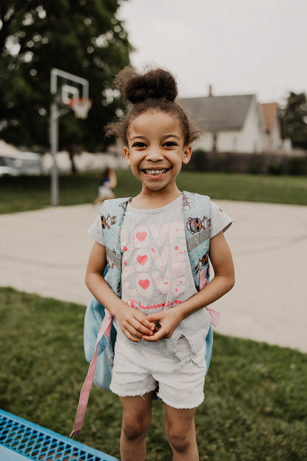 Smiling black girl wearing backpack arrives at Boys & Girls Club of Bloomington-Normal